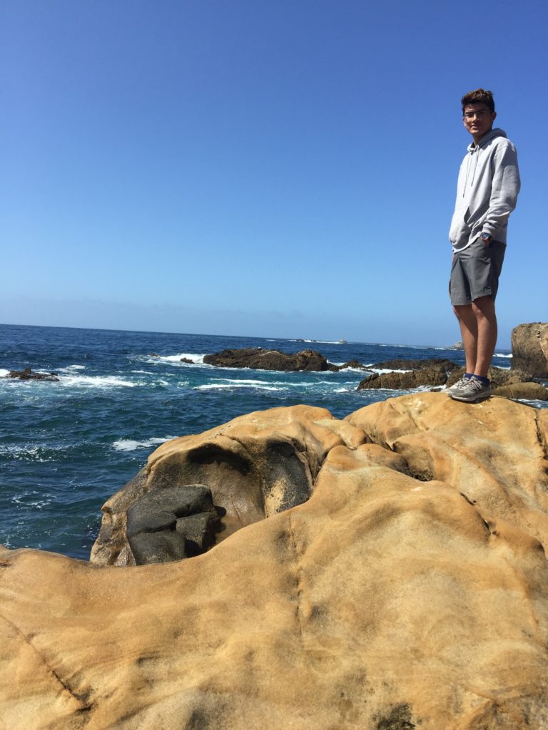 Cameron standing on some rocks at the seashore in Monterey Bay.